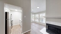This 2-bedroom, 1-bathroom single-floor residence offers a thoughtfully arranged layout that maximizes comfort and functionality. The combined kitchen and living room serves as the heart of the home, anchored by a striking fireplace with a clean white mantle and modern black surround. Vaulted ceilings in the living area add a sense of openness, while wood-look flooring and a sliding glass door with vertical blinds lead to an outdoor area, inviting natural light throughout. A bay window nook adjacent to the living space provides additional brightness and a charming architectural detail.

The galley-style kitchen is equipped with stainless steel appliances, white cabinetry, and light countertops, all set atop durable wood-look flooring. Both bedrooms are carpeted for comfort and include ceiling fans. The primary bedroom features natural light from dual windows, while the second bedroom includes a sliding closet and an additional two closets are found throughout the home for ample storage. A connecting hallway ties the layout together efficiently.

The full bathroom is finished with a white vanity, tiled shower-tub combo, brushed nickel fixtures, and wood-look herringbone flooring, offering a clean and polished aesthetic throughout.