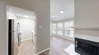 This 2-bedroom, 1-bathroom single-floor residence offers a thoughtfully arranged layout that maximizes comfort and functionality. The combined kitchen and living room serves as the heart of the home, anchored by a striking fireplace with a clean white mantle and modern black surround. Vaulted ceilings in the living area add a sense of openness, while wood-look flooring and a sliding glass door with vertical blinds lead to an outdoor area, inviting natural light throughout. A bay window nook adjacent to the living space provides additional brightness and a charming architectural detail.

The galley-style kitchen is equipped with stainless steel appliances, white cabinetry, and light countertops, all set atop durable wood-look flooring. Both bedrooms are carpeted for comfort and include ceiling fans. The primary bedroom features natural light from dual windows, while the second bedroom includes a sliding closet and an additional two closets are found throughout the home for ample storage. A connecting hallway ties the layout together efficiently.

The full bathroom is finished with a white vanity, tiled shower-tub combo, brushed nickel fixtures, and wood-look herringbone flooring, offering a clean and polished aesthetic throughout.
