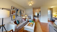 Located at 8230 Stonebrook Terr in Raleigh, NC, this single-floor residence offers a well-designed layout with warm hardwood-style flooring throughout the main living areas. The living room is a comfortable, open space featuring a ceiling fan, a sliding glass door that leads to a private balcony with outdoor views, and ample room for both lounging and entertaining. A hallway connects the living area seamlessly to the rest of the home. The galley-style kitchen is outfitted with white cabinetry, light countertops, and full appliances, and flows directly into a sunny dining nook surrounded by large windows that fill the space with natural light. Two bathrooms serve the home: one features a single-sink vanity with white cabinetry and a shower-tub combination, while the second offers a matching vanity setup alongside a glass-enclosed walk-in shower, both finished with light tile flooring. The bedrooms vary in character — one showcases a tray ceiling with a ceiling fan and a walk-in closet, another features a bold dark accent wall with closet access, and a third offers a bright window with serene outdoor views. Ceiling fans are present throughout, contributing to a consistently comfortable atmosphere across the entire residence.