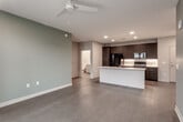 This single-floor residence in North Kansas City, MO, presents a contemporary design with a well-organized layout and modern finishes throughout. The open-concept living and kitchen area serves as the heart of the unit, where smooth hard-surface flooring, recessed lighting, and a ceiling fan create a clean, functional atmosphere. A soft sage-green accent wall adds a subtle touch of color to the living space.

The kitchen is outfitted with bold dark cabinetry extending to the ceiling, a white quartz island with an integrated sink, a white subway tile backsplash, and a full suite of black appliances, including a refrigerator, range, and microwave. The island provides additional seating and prep space, making the kitchen both practical and visually striking.

The bedrooms feature plush carpeting and ceiling fans, with one bedroom offering direct access to a walk-in closet equipped with wire shelving systems. Two bathrooms serve the unit: one features a glass-enclosed walk-in shower and a sleek white vanity, while the second includes a full soaking tub and shower combination with a matching white vanity. Both bathrooms are finished with light wood-look tile flooring and brushed nickel hardware. A dedicated laundry area houses a full-size top-loading washer and dryer.