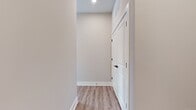This well-designed apartment offers 1150 square feet of comfortable living space on a single floor. The layout includes two bedrooms, two full bathrooms, and an open-concept kitchen and living room area, ideal for modern lifestyles. The primary bedroom is generously sized at 180 square feet, providing ample space for relaxation and storage.

The interior showcases contemporary design elements, featuring neutral-toned walls and sleek wood-look flooring throughout. Large windows, as seen in the image, allow for abundant natural light, creating a bright and airy atmosphere. The windows are equipped with horizontal blinds, offering easy light control and privacy.

The space boasts clean lines and a minimalist aesthetic, with recessed lighting and subtle wall-mounted fixtures. Multiple electrical outlets are strategically placed, catering to various layout possibilities and modern tech needs. The apartment's open floor plan promotes a sense of spaciousness and flexibility in furniture arrangement.

Storage needs are addressed with two dedicated closet spaces, while a hallway provides easy navigation between rooms. The overall design emphasizes functionality and comfort, making this apartment an attractive option for those seeking a modern, low-maintenance living space in a convenient single-story layout.