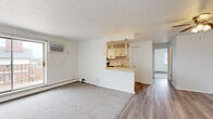 Located at 17920 Detroit Ave in Lakewood, OH, this 2-bedroom, 1-bathroom unit offers a practical and well-organized single-floor layout. The living room is a generous, carpeted space anchored by a large sliding window that fills the room with natural light and offers views of the surrounding neighborhood. A wall-unit air conditioner and baseboard heating ensure year-round comfort. The living area flows seamlessly into the kitchen via a pass-through counter with pendant lighting overhead. The kitchen features stainless steel appliances, including an electric range and over-the-range microwave, light cabinetry, a subway tile backsplash, and hardwood-style flooring. A hallway connects the main living areas to the bedrooms and bathroom. The primary bedroom is a well-proportioned, carpeted room with a mirrored sliding-door closet and a bright window overlooking the exterior. The second bedroom is similarly finished with carpet, a window with blinds, and baseboard heating. The bathroom is cleanly appointed with large-format tile surrounding the shower-tub combination, tile flooring, and standard white fixtures. Throughout the unit, crisp white walls and neutral finishes create a clean, bright ambiance.
