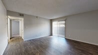 Located at 5038 S Hardy Dr in Tempe, Arizona, this single-story, two-bedroom, one-bathroom residence offers a functional and well-appointed layout. The living room is a welcoming space featuring rich wood-style laminate flooring, neutral gray walls, a textured ceiling, and a large sliding glass door fitted with vertical blinds that allows natural light to fill the room. The kitchen is efficiently designed with gray shaker-style cabinetry, a stainless steel refrigerator, a dishwasher, a tiled backsplash, and light wood-style flooring, complemented by a countertop peninsula that offers additional workspace. Both bedrooms are carpeted and feature textured ceilings, neutral tones, and windows with blinds that bring in natural light. The primary bedroom includes a sliding-door closet, providing practical storage. The shared full bathroom is clean and modern, featuring wood-style tile flooring, a gray vanity with a white sink, and a tub-shower combination with white tile surround. A hallway connects the main living areas to the bedrooms and bathroom, contributing to the home's cohesive and efficient flow. The overall aesthetic is clean and contemporary throughout.