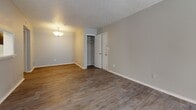 This single-story unit in Stone Mountain, Georgia, offers a practical and well-organized layout across several distinct living areas. The main living space features wood-style plank flooring and neutral-toned walls, complemented by a textured ceiling and a pendant light fixture. A coat closet is conveniently located near the front entry door, providing immediate storage upon arrival.

The galley-style kitchen is equipped with dark espresso cabinetry paired with white countertops, a black range, and a tall window fitted with horizontal blinds that introduces natural light into the space. The kitchen's efficient corridor layout maximizes counter and storage space on both sides.

The bedrooms are finished with wall-to-wall carpeting, creating a softer, quieter atmosphere. Each room benefits from generous closet space, including a walk-in closet with built-in shelving that offers organized storage. One bedroom also features a door providing access to an exterior area with natural light.

The bathroom is finished with wood-style tile flooring, a tiled tub and shower combination, a dark-cabinetry vanity with a white countertop, and a large mirror above the sink. Throughout the unit, the neutral color palette and consistent finishes create a cohesive, functional living environment.