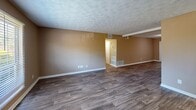 Located at 2560 Delk Rd in Marietta, Georgia, this single-floor unit offers five bedrooms and two full bathrooms across a well-organized and functional floor plan. The open living room features durable wood-look vinyl flooring, warm neutral-toned walls, and a textured ceiling, creating a welcoming common area. Adjacent to the living room, the kitchen is equipped with warm wood cabinetry, gray laminate countertops, a gas range, a double basin sink, and a breakfast bar peninsula — ideal for casual dining and meal preparation. Bedrooms are carpeted and finished with the same neutral color palette, offering a cozy atmosphere. The spacious primary bedroom includes a walk-in closet with dual hanging rods, providing generous storage. A second closet with carpeted flooring and built-in shelving adds further storage convenience. The two bathrooms offer distinct finishes: one features elegant marble-style tile surrounding a soaking tub and shower combo, while the other is appointed with wood-look flooring, a vanity with countertop space, and a tiled tub-shower unit. Two hallways connect the rooms efficiently throughout the layout, and multiple windows allow natural light to filter in, enhancing the overall brightness of the space.