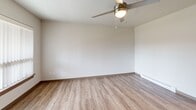 Located at 650 SE 162nd Ave in Portland, OR, this one-bedroom, one-bathroom apartment offers a practical and well-appointed layout across a single floor. Wood-look plank flooring runs consistently throughout the unit, complemented by neutral white walls and dark-toned interior doors with panel detailing, creating a clean, modern aesthetic.

The living room is a comfortable, open area featuring a ceiling fan with light fixture, a baseboard heater, and a large picture window fitted with vertical blinds that allows natural light to fill the space and provides views of the surrounding outdoor area. Adjacent to the living room, the combined dining and kitchen area is efficiently designed, featuring rich dark wood cabinetry, granite-style countertops, a full suite of black appliances including a refrigerator, dishwasher, and range, as well as a sink and recessed overhead lighting.

The bedroom is a well-sized private retreat, also with a ceiling fan, baseboard heating, and its own exterior-facing window. Three closets distributed throughout the unit offer generous storage options. The full bathroom includes a soaking tub, a vanity with dark wood cabinetry and granite-style countertops, and a towel bar, completing this functional and move-in-ready home.