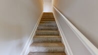 Located at 5817 Garden Village Court in Greensboro, NC, this two-story home offers a well-organized layout across two levels. The lower level houses the garage, which features built-in shelving, overhead fluorescent lighting, and a baseboard heater, providing both parking and additional storage. The main living level makes up the majority of the home's footprint and is where most daily living takes place. The open-concept kitchen and living area is a standout feature, showcasing a curved granite countertop island, white cabinetry, stainless steel appliances, and sleek pendant lighting. Light-toned wood-look flooring flows throughout the main living areas, complemented by crown molding and recessed lighting that add a refined touch. The three bedrooms are carpeted for comfort, with the spacious primary bedroom offering generous proportions and easy access to the hallway. Closets feature wire shelving systems for efficient organization, including a large walk-in closet with a natural window. The bathrooms are clean and functional, with one featuring a tub-shower combination. A dedicated laundry room with wire shelving and washer/dryer hookups adds everyday convenience. Carpeted staircases with white trim connect the levels, rounding out this practical and well-appointed home.