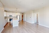 Located at 89 Hopkins Street in Wakefield, MA, this well-appointed 2-bedroom, 2-bathroom residence offers a thoughtfully designed open-concept layout with modern finishes throughout. Light-toned hardwood flooring flows seamlessly through the main living areas, creating a bright and cohesive aesthetic. The kitchen is a standout feature, showcasing white shaker cabinetry, a subway tile backsplash, stainless steel appliances, a built-in microwave, and a central island with pendant lighting — ideal for both cooking and casual dining. The kitchen opens directly into the spacious living area, which is bathed in natural light and offers access to a private balcony through sliding glass doors, providing pleasant outdoor views. A dedicated hallway leads to two well-sized bedrooms, each carpeted for comfort and featuring large windows that bring in ample natural light. The primary bedroom includes a walk-in closet with built-in wire shelving. Both bathrooms are finished with wood-look tile flooring, white vanity cabinetry, and a shower-tub combination. The unit also includes two closets for additional storage. Recessed lighting and a clean, neutral color palette give the entire space a polished, move-in-ready feel.