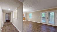 Located in Atlanta, GA, this well-appointed one-bedroom, one-bathroom residence offers a thoughtfully designed single-floor layout. Rich, dark hardwood flooring flows throughout the main living areas, creating a warm and cohesive aesthetic that contrasts beautifully with the neutral beige walls and crisp white crown molding and baseboards.

The spacious living area is a standout feature, highlighted by an elegantly patterned ceiling, multiple windows that invite abundant natural light, and a set of French doors that open to views of lush greenery — ideal for enjoying the outdoors. A convenient pass-through window connects the living area to the kitchen, adding an open, airy feel.

The kitchen is well-equipped with warm honey-toned wood cabinetry, granite-style countertops, a classic subway tile backsplash, and black appliances including a range, dishwasher, and refrigerator. Light tile flooring completes the practical yet inviting kitchen space.

The bedroom offers a comfortable retreat with hardwood floors, a ceiling fan with light fixture, and a window framing natural views. The full bathroom features a wood vanity with granite-style countertop, a large mirror, tile flooring, and a tub-shower combination. A dedicated closet and hallway with tile flooring round out this well-organized home.