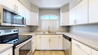 Located at 5151 E Guadalupe Rd in Phoenix, AZ, this two-bedroom, two-bathroom residence offers a thoughtfully laid-out single-level floor plan. The living room serves as the heart of the home, highlighted by vaulted ceilings, a ceiling fan, a fireplace with a tiled hearth, built-in arched wall niches, and a sliding glass door that invites natural light and outdoor access. Arched architectural details and a half-wall partition add character and define the transition between living spaces.

The kitchen is efficiently designed in a U-shape configuration, featuring white cabinetry, light countertops, wood-look flooring, and stainless steel appliances including a range, microwave, and dishwasher. An arched window above the sink provides natural light, enhancing the clean, bright aesthetic.

The primary bedroom is generously sized with vaulted ceilings, a ceiling fan, carpet flooring, and a large window with vertical blinds. It is complemented by a spacious walk-in closet outfitted with wire shelving on multiple walls. The second bedroom is carpeted and well-proportioned. Both bathrooms include wood-look flooring, with one featuring a full soaking tub and shower combination. A dedicated laundry area with side-by-side units is also included.