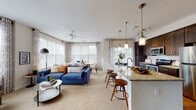 This well-appointed single-floor residence offers a thoughtfully designed open-concept layout that seamlessly connects the living, dining, and kitchen areas. The living room is filled with natural light from multiple large windows dressed with elegant curtains, and features plush carpeting, a ceiling fan, and generous space for both relaxing and entertaining. A stylish blue accent wall adds a contemporary touch to the space.

The kitchen is a standout feature, outfitted with rich dark-wood cabinetry, granite countertops, a classic subway tile backsplash, and a full suite of stainless steel appliances including a range, microwave, and refrigerator. Hardwood flooring runs throughout the kitchen, which also benefits from excellent natural light. A peninsula with bar seating and pendant lighting creates a natural transition into the living and dining areas.

The primary bedroom is a serene retreat with large windows overlooking greenery and soft carpeting underfoot. A second bedroom features a bold chevron-patterned accent wall in deep blue, adding a dramatic design element. Both bathrooms are well-finished, with one featuring dark cabinetry, granite vanity tops, hardwood-style flooring, and a glass-enclosed walk-in shower. A dedicated laundry room with a full-size washer and dryer and built-in shelving completes this functional and stylish home.
