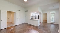 Located at 14885 Memorial Dr in Houston, TX, this well-appointed two-bedroom, two-bathroom residence offers a thoughtfully designed single-floor layout. The open living area makes a striking impression with its distinctive herringbone-patterned luxury vinyl plank flooring and large windows that flood the space with natural light and offer lush, tree-lined views. The kitchen is a standout feature, boasting white shaker cabinetry with brushed gold hardware, quartz countertops, a marble-style tile backsplash, a stainless steel undermount sink with a gold-toned faucet, and a full suite of stainless steel appliances including a refrigerator, range, microwave, and dishwasher. A tray ceiling adds architectural interest overhead. Both bedrooms are carpeted and equipped with ceiling fans; the primary bedroom includes a spacious walk-in closet with wire shelving. The bathrooms continue the home's clean aesthetic with wood-look herringbone flooring, white vanities, and brushed gold accents. Additional storage is provided by two closets throughout the unit. The overall palette of crisp whites and warm neutrals creates a bright, modern ambiance throughout.