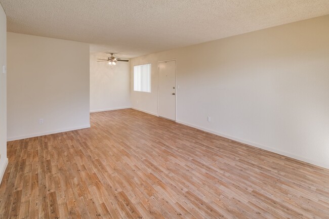 Imagen de la sala de estar con pisos de tablones estilo madera y una vista del área de comedor con ventilador de techo. - Casa De La Mesa