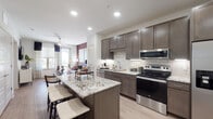 This well-appointed single-floor residence offers a thoughtfully designed open-concept layout that seamlessly connects the kitchen, dining, and living areas. The kitchen is a standout feature, showcasing rich dark-toned cabinetry, striking granite countertops with bold veining, a classic white subway tile backsplash, and a full suite of stainless steel appliances including a French door refrigerator, electric range, built-in microwave, and dishwasher. A generously sized kitchen island with bar seating provides additional prep space and a casual dining option. Light wood-look flooring runs throughout the main living areas, complementing the clean, contemporary aesthetic. The living room is bright and welcoming, featuring large windows that invite natural light, a ceiling fan, and a bold accent wall that adds a warm, modern touch. The bedroom is a comfortable retreat with plush carpeting, natural light from dual windows, and ample wall space. The en-suite bathroom is finished with matching dark cabinetry, granite countertops, and light flooring, leading directly into a spacious walk-in closet with built-in shelving and hanging storage. Recessed lighting throughout enhances the modern, polished ambiance of this well-designed residence.