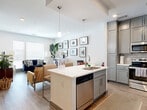 Located at 550 E Brooklyn Village Ave in Charlotte, NC, this well-appointed one-bedroom, one-bathroom residence offers a thoughtfully designed open-concept layout with modern finishes throughout. The combined kitchen and living area forms the heart of the home, anchored by a central island with a white quartz countertop, stainless steel sink, and built-in dishwasher — ideal for both casual dining and entertaining. The kitchen features floor-to-ceiling gray shaker cabinets, a subway tile backsplash, and a full suite of stainless steel appliances including a range, microwave, and refrigerator. Pendant lighting accents the island, adding a contemporary touch. Wide-plank wood-style flooring flows throughout the main living area, which is bathed in natural light from large windows. The bedroom offers a comfortable, carpeted retreat complete with a ceiling fan, recessed lighting, and access to a generously sized walk-in closet with full rod systems. The full bathroom presents a clean, neutral aesthetic with large-format tile flooring, a white vanity with ample storage, and a tiled soaking tub and shower combination. The overall palette of whites, grays, and warm wood tones creates a cohesive and modern ambiance throughout this Charlotte residence.