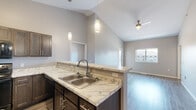Located at 2200 S Ellis Rd in Sioux Falls, South Dakota, this single-floor unit offers a thoughtfully designed open-concept layout with modern finishes. The vaulted ceilings in the main living area create an impressive sense of height and volume, complemented by durable wood-look plank flooring and abundant natural light streaming through large windows. A ceiling fan adds both style and function to the airy living space, which also features a sliding door providing outdoor access.

The kitchen is well-appointed with rich dark-stained cabinetry, marble-patterned countertops, black appliances including a refrigerator, range, and over-the-range microwave, and a double-basin sink. Pendant lighting over the kitchen peninsula adds a refined touch and connects the kitchen seamlessly to the living area.

The bedrooms are carpeted for comfort and feature neutral tones with ample natural light from exterior-facing windows. At least one bedroom includes a dedicated walk-in closet, offering practical storage solutions.

The bathrooms are finished with wood-look flooring, dark vanity cabinetry, and clean white fixtures. One bathroom features a full tub-shower combination, while another includes a vanity with a lighted mirror. The overall palette of warm grays and neutral tones throughout the unit creates a cohesive, contemporary aesthetic.