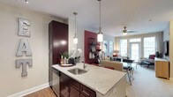 This well-appointed single-floor residence showcases a cohesive modern design throughout its thoughtfully laid-out spaces. The open-concept kitchen is a standout feature, equipped with rich dark cabinetry, granite countertops, and a central island with an undermount sink illuminated by pendant lighting. Stainless steel appliances, including a gas range, microwave, and refrigerator, complement the subway tile backsplash and wood-style flooring, creating a functional yet refined cooking environment.

The kitchen flows seamlessly into the living area, which is bathed in natural light from large windows and a glass door offering outdoor views. A ceiling fan adds comfort to the open layout, while neutral tones and accent walls provide a warm, inviting atmosphere throughout.

The bedroom features a walk-in closet with built-in shelving and an accent wall, lending a sense of character and practicality. A second bedroom or sitting room benefits from generous window light. The bathroom is finished with subway tile surrounding a soaking tub, dark accent walls, wood-style flooring, and a granite-topped vanity. A dedicated laundry area with side-by-side washer and dryer and wire shelving rounds out the home's practical amenities.