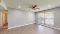 Located at 1013 Town Branch Rd in Graham, NC, this single-floor, three-bedroom, one-bathroom home offers a practical and well-organized layout across a compact footprint. Neutral gray walls and crisp white baseboards are consistent throughout, lending a clean and cohesive aesthetic to every room.

The living area features light luxury vinyl plank flooring, recessed lighting, and a ceiling fan, while a large window provides natural light and views of surrounding greenery. This open feel carries into the primary bedroom, which is notably spacious and also includes a ceiling fan, LVP flooring, and a window overlooking the outdoors. The two additional bedrooms are finished with plush carpet and each includes a closet with built-in hanging rods — one featuring double bi-fold doors for easy access.

The galley-style kitchen is efficiently designed with white cabinetry, granite-look countertops, and black appliances including a refrigerator, range, and microwave. A window above the counter brings in natural light. The hallway connects all rooms with recessed lighting and continues the LVP flooring.

The full bathroom is straightforward and functional, offering a tub-shower combination with white surround. A utility room and additional hallway storage round out the home's practical layout.