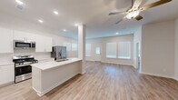 Located at 17003 Telge Road in Cypress, TX, this single-story, 3-bedroom, 3-bathroom home offers a clean, modern design with a bright and cohesive aesthetic throughout. The open-concept kitchen and living area serves as the heart of the home, featuring white cabinetry, a stainless steel refrigerator with ice and water dispenser, white quartz countertops with a peninsula, subway tile backsplash, and recessed lighting. Light wood-style flooring flows seamlessly through the main living spaces, complemented by crisp white walls and multiple windows dressed with horizontal blinds that allow generous natural light. The living area is further enhanced by a ceiling fan and elevated ceilings that add a sense of spaciousness. Each of the three bedrooms offers wood-style flooring and ceiling fans, with the primary bedroom featuring a vaulted ceiling and a walk-in closet with dual hanging rods. All three bedrooms are served by their own bathrooms. A dedicated laundry room houses a full-size washer and dryer with overhead shelving. The attached two-car garage provides ample storage and parking with an automatic garage door opener. Three closets throughout the home offer practical storage solutions, and two hallways connect the layout efficiently.