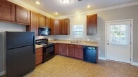 Located at 657 Rain Forest Rd in Knoxville, Tennessee, this two-story home offers a well-organized layout with thoughtful details throughout both levels. The main floor features an open-concept design connecting the living room and kitchen, separated by a wide archway. The kitchen is equipped with rich dark wood cabinetry, a black refrigerator, and tile-style flooring, while the adjoining living area is finished with neutral-toned carpet. Crown molding runs consistently throughout the home, adding a polished architectural touch. A staircase with a wooden banister connects the main floor to the upper level, where the bedrooms are located. Each bedroom features plush carpet, crown molding, and ceiling fixtures. The primary bedroom includes two doors — one leading to a spacious walk-in closet outfitted with wire shelving systems, and another to an additional room. A full bathroom is also present, featuring tile flooring, a vanity, and a toilet. A dedicated laundry closet with hookups is conveniently located near the bathroom. Natural light filters in through multiple windows, and the consistent use of soft gray and warm beige tones throughout creates a cohesive, neutral palette across the entire home.