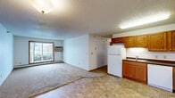 Located in Albertville, MN, this three-bedroom, one-bathroom single-floor unit offers a practical and comfortable layout. The open-concept kitchen and living area serves as the heart of the home, where tile flooring transitions seamlessly between spaces. The kitchen is well-equipped with warm oak cabinetry, dark countertops, a double sink, and white appliances including a refrigerator, dishwasher, and electric range — providing ample functionality for everyday cooking. The living area features carpeting and a large sliding window that invites natural light and outdoor views. Each of the three bedrooms is carpeted and features wood-framed windows with vertical blinds, baseboard heating, and individual closets with wire shelving systems. Five total closets throughout the unit ensure generous storage capacity. The full bathroom is finished with tile flooring, an oak vanity with a single sink, and a combined tub and shower. Textured ceilings are consistent throughout the unit, complemented by clean white walls and warm wood trim. A hallway connects the bedroom wing to the main living areas, contributing to an efficient and well-organized floor plan suited for a variety of living arrangements.