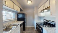 This two-story residence in Memphis, Tennessee offers a functional and well-organized layout across two levels. The galley-style kitchen features white cabinetry with modern hardware, marble-patterned countertops, wood-look vinyl flooring, and black and stainless steel appliances including an electric range, dishwasher, and refrigerator. A textured ceiling and a window providing natural light complete the space.

The living areas are finished with neutral gray carpet, creating a cohesive look throughout the home. Soft blue-gray walls are consistent across both floors, lending a calm, unified aesthetic. Staircase access connects the two levels, with the upper floor housing the bedrooms. Both bedrooms are carpeted and feature windows that allow natural light in, with textured ceilings adding architectural detail.

The full bathroom includes a white vanity with marble-patterned countertops, a large mirror, and wood-look flooring. The half bath mirrors this design with matching cabinetry and countertops. Additional utility space houses the water heater. Overall, the home presents a clean, move-in ready interior with consistent finishes throughout.