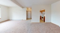 Located at 5420 W Barnes Rd in Spokane, Washington, Unit 216 is a well-laid-out single-floor residence offering a comfortable and functional living environment. The open living area is finished with soft wall-to-wall carpeting and neutral walls that create a bright, welcoming atmosphere. A baseboard heating system runs along the perimeter, ensuring year-round comfort. A glass-paneled exterior door allows natural light to filter into the living space, while a bedroom window frames a lush, green outdoor view. The kitchen is thoughtfully designed with warm oak cabinetry, tile countertops, and a peninsula-style breakfast bar that opens to the living area through a charming arched passageway. White appliances — including a refrigerator, electric range, microwave, and dishwasher — are all included. Light tile flooring throughout the kitchen adds a clean contrast to the carpeted living spaces. The bathroom features a vanity with tile-accented countertops and convenient access to an in-unit laundry closet equipped with a washer. The bedroom is generously sized with plush carpeting, a large window overlooking greenery, and a baseboard heater. This residence offers a practical and comfortable layout in a residential Spokane neighborhood.