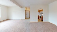 Located at 5420 W Barnes Rd in Spokane, Washington, Unit 216 is a well-laid-out single-floor residence offering a comfortable and functional living environment. The open living area is finished with soft wall-to-wall carpeting and neutral walls that create a bright, welcoming atmosphere. A baseboard heating system runs along the perimeter, ensuring year-round comfort. A glass-paneled exterior door allows natural light to filter into the living space, while a bedroom window frames a lush, green outdoor view. The kitchen is thoughtfully designed with warm oak cabinetry, tile countertops, and a peninsula-style breakfast bar that opens to the living area through a charming arched passageway. White appliances — including a refrigerator, electric range, microwave, and dishwasher — are all included. Light tile flooring throughout the kitchen adds a clean contrast to the carpeted living spaces. The bathroom features a vanity with tile-accented countertops and convenient access to an in-unit laundry closet equipped with a washer. The bedroom is generously sized with plush carpeting, a large window overlooking greenery, and a baseboard heater. This residence offers a practical and comfortable layout in a residential Spokane neighborhood.
