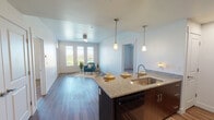 This well-appointed single-floor residence offers a thoughtfully designed open-concept layout that seamlessly connects the kitchen and living area. The kitchen is a standout feature, equipped with dark espresso cabinetry, granite countertops, a large island with an undermount sink, pendant lighting, and black appliances including a refrigerator, electric range, and microwave. Wood-look luxury vinyl plank flooring runs throughout the main living areas, adding warmth and continuity to the space.

The living area is bright and inviting, benefiting from natural light through large windows dressed with plantation shutters and a ceiling fan for added comfort. Two generously sized bedrooms are finished with plush carpeting, ceiling fans, and windows that offer outdoor views, providing a calm and restful atmosphere. Each bedroom includes closet access, with one featuring direct sightlines to the kitchen area.

Two bathrooms serve the unit, each finished with dark wood vanities, granite countertops, undermount sinks, and wood-look flooring. One bathroom features a shower with a curtain rod, while the other includes a full soaking tub and shower combination. Clean white walls and neutral tones throughout the space create a modern, cohesive aesthetic that is both functional and inviting.