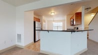 This multi-story residence is thoughtfully laid out across three floors, offering a functional and comfortable living environment throughout. The kitchen serves as a central feature, equipped with warm-toned wooden cabinetry, dark granite countertops, stainless steel appliances including a gas range, microwave, and refrigerator, and tile flooring. A breakfast bar with decorative iron supports connects the kitchen to the adjoining living area, which is bathed in natural light from large windows and finished with neutral wall-to-wall carpeting. A pendant chandelier adds a refined touch above the dining area nearby. The half bathroom on the main level features a pedestal sink and round mirror, offering a clean, minimalist design. Upper-level bedrooms are generously sized with soft carpet, vaulted ceilings, ceiling fans, and windows that invite natural light. One bedroom features a notable vaulted ceiling with a ceiling fan and a bright outlook to the outdoors. Bathrooms on this level include a full bath with a tub-shower combo and warm tile flooring, as well as a secondary bath with a vanity and large mirror. The lower level provides additional carpeted room space, suitable for flexible use, along with its own bathroom. Six-panel interior doors and neutral wall tones create a cohesive, understated aesthetic throughout the home.