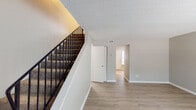 Located at 1304 Cornell Ave in Dothan, Alabama, this two-story home offers a practical and well-organized layout across both levels. The main floor features light-toned luxury vinyl plank flooring throughout the living and entry areas, lending a clean and modern aesthetic. A staircase with a sleek black metal railing leads to the upper level, adding a contemporary architectural detail to the interior. The living area is open and bright, with natural light filtering in through blinds-covered windows and neutral wall tones creating a calm, welcoming ambiance. Textured ceilings are present throughout the home.

The kitchen is equipped with stainless steel appliances, including a refrigerator, range, and over-the-range microwave, complemented by white cabinetry and a classic subway tile backsplash. The main level also includes a bathroom featuring a marble-topped vanity with white cabinetry and wood-look flooring.

Upstairs, the bedrooms are finished with wall-to-wall carpet and feature louvered bifold closet doors, providing ample storage. The upper-level hallway, accented with warm yellow tones, connects the bedrooms and a full bathroom outfitted with a marble-top vanity and light wood flooring. The upper bathroom offers convenient access to the hallway and staircase landing.