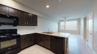 Located at 11706 N Lamar Blvd in Austin, TX, this single-floor unit offers a well-designed, open-concept layout that seamlessly connects the kitchen and living area. The kitchen is a standout feature, equipped with rich dark espresso cabinetry, light countertops, and a full suite of black appliances including a refrigerator, electric range, over-the-range microwave, and dishwasher. A peninsula with a double-basin sink serves as both a functional workspace and a natural divider between the kitchen and the living space. Light tile flooring runs throughout the unit, creating a clean and cohesive look. The open living area benefits from recessed lighting and a ceiling fan, contributing to a comfortable and well-lit environment. Natural light filters in through windows fitted with horizontal blinds. The bathroom features a single-sink vanity with dark cabinetry matching the kitchen, a large mirror, light countertop, and tile flooring consistent with the rest of the unit. A separate room with tile flooring and a window with blinds provides a versatile space suitable for use as a bedroom or office. The neutral color palette and consistent finishes throughout give the unit a cohesive, modern feel.