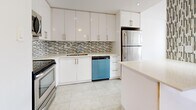 This thoughtfully designed 1-bedroom, 1-bathroom unit offers a smart and functional layout across a single floor. The open-concept kitchen and living area serves as the heart of the unit, where a modern kitchen features sleek white cabinetry extending to the ceiling, a mosaic tile backsplash, light stone countertops, stainless steel appliances including a full-size refrigerator and range, and a peninsula that seamlessly connects to the living space. The kitchen is finished with large-format ceramic tile flooring, while warm-toned parquet wood flooring flows throughout the rest of the unit. The living room is bright and airy, benefiting from expansive floor-to-ceiling windows and access to a balcony, offering open urban views of the surrounding cityscape. The bedroom is a comfortable and well-proportioned retreat with a large double closet, a window with city views, and the same polished parquet flooring. The bathroom is finished with textured stone-look wall tiles, a soaker tub with shower, a white vanity with a stone countertop, and recessed lighting. A decorative accent wall adds a touch of character to the living area. The unit is enhanced by abundant natural light throughout.