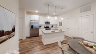 This single-story residence offers a thoughtfully designed open-concept layout finished with contemporary details throughout. The kitchen serves as a central highlight, showcasing crisp white shaker cabinetry, a subway tile backsplash, granite-topped counters, and a large center island with a built-in sink. Stainless steel appliances — including a French door refrigerator, electric range, and built-in microwave — complete the space. Globe pendant lights hang above the island, adding a modern touch, while wood-look flooring extends seamlessly into the adjacent dining area.

The living room is bright and welcoming, with natural light filtering through large windows dressed with grommet-panel curtains. Recessed lighting and neutral walls create a versatile backdrop throughout the common areas.

The bedrooms are comfortably sized, featuring plush carpet flooring and windows that allow ample natural light. The primary bedroom connects to an en-suite bathroom with a double-sink granite vanity, white cabinetry, and wood-look flooring. A secondary bathroom mirrors the same refined aesthetic, offering a single-sink vanity and a tub-shower combination. Together, these spaces deliver a clean, cohesive, and move-in-ready living environment.