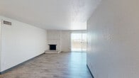 Located at 1251 S Bellaire St in Denver, CO, this two-bedroom, two-bathroom residence offers a well-organized single-level layout with wood-style flooring throughout. The living room serves as the heart of the home, highlighted by a white-painted brick fireplace wall and a sliding glass door that opens to a balcony, flooding the space with natural light. The bedrooms are comfortably sized, with the primary bedroom featuring dual closets with louvered bifold doors and a window dressed with vertical blinds. The secondary bedroom offers a bright window framing striking urban skyline views, including prominent Denver high-rises. Both bathrooms are finished with white subway tile wainscoting, granite-style countertops, and well-lit vanity mirrors. A connecting hallway links the bedrooms and bathrooms, contributing to a functional and efficient floor plan. The neutral color palette of whites and warm beiges, paired with consistent wood-style flooring and dark baseboards, gives the residence a clean, cohesive aesthetic. With its elevated position offering city views and classic architectural details like the brick fireplace, this Denver residence combines urban convenience with comfortable, practical living.