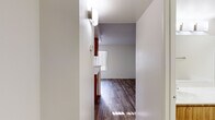 Located at 333 W Van Buren St in Avondale, Arizona, this single-floor unit offers a efficiently designed layout comprising a kitchen, bathroom, closet, and hallway. Wood-look plank flooring runs throughout the space, lending a warm, cohesive feel to every room.

The kitchen is equipped with a white electric range and refrigerator, complemented by warm wood-toned cabinetry that extends overhead for ample storage. A peninsula with a light-colored countertop and sink serves as a natural divider between the kitchen and the open living area, offering both additional prep space and a casual dining or workspace option.

The living area benefits from a large window fitted with vertical blinds, allowing natural light to fill the room and providing a view of the outdoor surroundings. The textured ceiling adds a subtle architectural detail to the otherwise clean, white walls.

The hallway connects the main living space to the bathroom and closet. The bathroom features wood-toned cabinetry, a light stone-finish countertop, wood-look flooring, and brushed nickel hardware and fixtures, maintaining the consistent design language found throughout the unit.

Overall, the space presents a straightforward, functional layout with cohesive finishes, making it a practical and easy-to-navigate unit in Avondale, AZ.