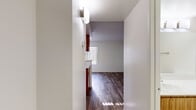 Located at 333 W Van Buren St in Avondale, Arizona, this single-floor unit offers a efficiently designed layout comprising a kitchen, bathroom, closet, and hallway. Wood-look plank flooring runs throughout the space, lending a warm, cohesive feel to every room.

The kitchen is equipped with a white electric range and refrigerator, complemented by warm wood-toned cabinetry that extends overhead for ample storage. A peninsula with a light-colored countertop and sink serves as a natural divider between the kitchen and the open living area, offering both additional prep space and a casual dining or workspace option.

The living area benefits from a large window fitted with vertical blinds, allowing natural light to fill the room and providing a view of the outdoor surroundings. The textured ceiling adds a subtle architectural detail to the otherwise clean, white walls.

The hallway connects the main living space to the bathroom and closet. The bathroom features wood-toned cabinetry, a light stone-finish countertop, wood-look flooring, and brushed nickel hardware and fixtures, maintaining the consistent design language found throughout the unit.

Overall, the space presents a straightforward, functional layout with cohesive finishes, making it a practical and easy-to-navigate unit in Avondale, AZ.