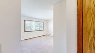 Located at 1631 Carl St in Lauderdale, Minnesota, this one-bedroom, one-bathroom unit offers a functional and well-organized single-floor layout. The kitchen is a standout feature, equipped with rich, warm-toned wood cabinetry, a white electric range, a full-size refrigerator, and a stainless steel sink set against classic white subway tile backsplash. Light wood-style flooring runs through the kitchen and into the adjoining living area, creating a seamless and bright open feel. Natural light filters in through multiple windows dressed with horizontal blinds, lending the space a welcoming atmosphere. The living area is climate-controlled with a wall-mounted AC unit and baseboard heating throughout. The bedroom offers plush carpeting underfoot, a ceiling fan with light fixture, a generously sized double-door closet, and a window that brings in natural light. The bathroom features a full soaking tub with a tile surround in neutral cream tones, complemented by bronze fixtures and a white vanity. Clean white walls throughout the unit create a neutral, move-in-ready canvas. The overall layout, as seen in the dollhouse view, is compact yet efficient, making excellent use of every square foot.