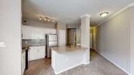 Located at 455 Elmcroft Blvd in Rockville, MD, this single-floor, 3-bedroom, 2-bathroom residence offers a well-organized layout with a thoughtful mix of finishes throughout. The kitchen is a standout, featuring white cabinetry, a herringbone tile backsplash, stainless steel refrigerator, and a peninsula with a granite countertop and integrated sink — seamlessly connecting to the adjacent living area, which is finished with warm-toned carpet. Crown molding and track lighting add refined detail to the common spaces.

The primary bedroom is generously sized, bathed in natural light from multiple windows with blinds, and accented by crown molding and a ceiling-mounted light fixture. The additional bedrooms are carpeted and well-proportioned, each with natural light and ample closet space, including double-door closets. Neutral gray walls create a clean, cohesive palette throughout.

Both bathrooms are finished with wood-look vinyl flooring, white vanities with integrated sinks, large mirrors, and tub-shower combinations with chrome fixtures. A dedicated laundry room houses a full-size washer and dryer with overhead wire shelving for additional storage. Two hallways connect the spaces efficiently, completing this functional and comfortable single-level home.