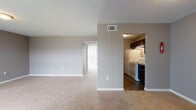 This single-floor, one-bedroom, one-bathroom unit offers a functional and comfortable layout with a cohesive neutral color palette of warm grays and beige tones. The open living area is generously sized, featuring plush wall-to-wall carpeting and a large window dressed with vertical blinds that allows natural light to fill the room. A dedicated entry point leads directly into this main living space, which flows seamlessly toward the rest of the unit.

The galley-style kitchen is efficiently designed with dark cabinetry lining both sides, granite-look countertops, and wood-style vinyl flooring. White appliances, including a refrigerator, electric range, and dishwasher, are included, and the kitchen opens directly into the living and dining area for easy accessibility.

The bedroom is a well-proportioned retreat featuring soft carpeting, a ceiling fan with integrated lighting, and a large sliding glass door fitted with vertical blinds that brings in natural light and outdoor views. The adjoining bathroom includes a white vanity with granite-look countertops, an undermount sink, and wood-style flooring, connecting conveniently to the bedroom. Overall, the unit presents a practical and move-in-ready living environment.