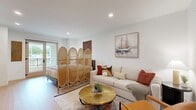 Located at 5050 Arrow Hwy in Montclair, CA, this thoughtfully designed one-bedroom, one-bathroom unit offers a well-organized single-floor layout that maximizes every inch of its compact footprint. Light-toned hardwood-style flooring runs throughout, complementing the bright white walls and recessed lighting that give the space a clean, modern aesthetic.

The open-plan living area flows seamlessly from the living room into the bedroom zone, separated by a decorative divider. The living area features ample space for comfortable seating and is bathed in natural light. The kitchen is well-appointed with light wood cabinetry, a herringbone tile backsplash, stainless steel appliances including a full-size refrigerator, dishwasher, microwave, and range, plus open shelving and white quartz countertops.

The bathroom offers a long vanity with a white quartz countertop, a wood-framed cabinet below, a large mirror, and a glass-enclosed walk-in shower, all finished with the same light flooring for a cohesive look. A louvered closet door provides convenient in-unit laundry access nearby.

Additional features include two closets for storage, a hallway connecting the main rooms, and a private balcony accessible from the living area, ideal for enjoying the Southern California climate.