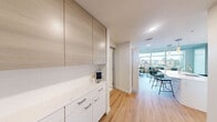 Located in Seattle's vibrant Belltown neighborhood, this modern one-bedroom, one-bathroom residence offers a thoughtfully designed layout with contemporary finishes throughout. Light hardwood flooring flows through the entry and kitchen-living area, complemented by exposed concrete ceilings that add an industrial-chic character to the space.

The open kitchen is well-appointed with flat-front cabinetry in a warm wood tone, white lower cabinets, quartz countertops, a full suite of stainless steel appliances, and an island that doubles as a breakfast bar. Floor-to-ceiling windows in the living area flood the space with natural light and frame sweeping views of the Seattle skyline, creating a bright and airy atmosphere.

The bedroom features plush carpeting, a dedicated track light, and large windows offering additional city views. A separate closet provides organized storage. The bathroom is finished with a white quartz dual-sink vanity, tile flooring, a full-length mirror, and clean, modern fixtures.

A dedicated closet and efficient use of space throughout make this residence a practical and stylish urban retreat in one of Seattle's most walkable and dynamic neighborhoods.