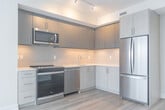 Located at 41 Johnson Street in Barrie, Ontario, this well-designed 2-bedroom, 2-bathroom unit offers a clean, modern aesthetic throughout its efficiently planned single-floor layout. Light-toned hardwood flooring runs consistently through the living spaces, contributing to a bright and cohesive feel.

The kitchen is appointed with two-tone cabinetry — combining matte grey upper cabinets with light wood-grain lower cabinets — complemented by white quartz countertops, a textured tile backsplash, a stainless steel sink, dishwasher, and a full-size French door refrigerator.

Both bedrooms feature large windows that frame elevated views of the surrounding Barrie neighbourhood, filling the rooms with natural light. The primary bedroom includes a sliding closet, while the second bedroom also benefits from generous window coverage and a built-in closet.

The two bathrooms maintain the unit's neutral palette, each featuring light wood-grain vanities with white quartz counters, large mirrors, and tile flooring. One bathroom includes an accessibility grab bar. Two hallways connect the spaces, keeping the floor plan organized and functional. The overall ambiance is contemporary and understated, with a consistent use of whites, light woods, and soft neutrals throughout.