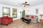 Located at 3424 Frankford Ave in Lubbock, Texas, this single-floor residence offers a practical and comfortable layout across several distinct living areas. The living room features wood-look laminate flooring, a ceiling fan, and a textured ceiling, with a window providing natural light and views of the surrounding greenery. The space accommodates a comfortable seating arrangement centered around a dark wood coffee table. The kitchen is well-equipped with warm wood cabinetry, light countertops, tile flooring, and a full suite of appliances including a dishwasher, electric range, and refrigerator. A breakfast bar provides additional counter space and casual dining options. The bedroom is carpeted and generously sized, featuring a ceiling fan, a window with an outdoor view, and ample room for furniture. A second area of the bedroom offers additional space, highlighted by neutral walls and built-in ventilation. The bathroom includes tile flooring, a wood vanity with a single sink, a wall-mounted mirror, overhead lighting, and a combination tub and shower. Throughout the home, a consistent neutral color palette and textured ceilings contribute to a cohesive and functional living environment.