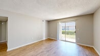 Located at 6115 N Davis Hwy in Pensacola, Florida, this single-floor, 2-bedroom, 2-bathroom residence offers a practical and comfortable layout. The living room is a bright, open space featuring warm wood-look flooring, neutral-toned walls, a textured ceiling, and a sliding glass door that fills the room with natural light and provides direct access to the outdoors. The kitchen is well-equipped with white shaker-style cabinetry, dark granite-look countertops, a double basin sink positioned beneath a natural light window, and a black dishwasher. Both bathrooms are finished consistently, featuring white vanity cabinetry, dark countertops, and a tiled shower-tub combination. A connecting hallway links the main living areas to the two bedrooms, each of which is carpeted for comfort and finished with neutral walls and textured ceilings. The primary bedroom is generously sized and includes a ceiling fan, a window for natural light, and access to a dedicated closet. The second bedroom is similarly styled. Two closets throughout the unit provide ample storage. The overall ambiance is clean, neutral, and move-in ready, offering a functional living environment in a well-situated Pensacola location.