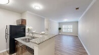 Located at 221 Embassy Dr in Fort Mill, SC, this single-story, three-bedroom, two-bathroom home offers a well-designed layout with a cohesive, neutral color palette throughout. The open-concept kitchen and living area serves as the heart of the home, featuring light wood-look luxury vinyl plank flooring and crown molding that adds a refined touch. The kitchen is appointed with rich dark cabinetry, granite countertops, black appliances including a range, microwave, and refrigerator, and a peninsula with bar seating that connects seamlessly to the living space. The living area is bright and open, providing ample room for a variety of furniture arrangements. The spacious primary bedroom features plush carpeting, a ceiling fan, and a window that allows in natural light. The two additional bedrooms are similarly finished with carpet and ceiling fans, offering comfortable and functional spaces. Both bathrooms are well-appointed, with one featuring a tub/shower combo and the other a single vanity with granite countertop, dark wood cabinetry, and hardwood-style flooring. A dedicated closet provides convenient storage. The home's consistent finishes and practical layout make it a comfortable and attractive residence in Fort Mill.