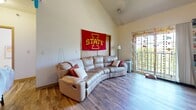 This two-story residence in Ames, Iowa offers six bedrooms and three bathrooms spread across two well-proportioned floors. The main floor provides the larger share of the living space and features a bright living room with striking vaulted ceilings, wood-look flooring, and a sliding glass door that opens to a balcony, filling the area with natural light. The upper floor contains additional bedrooms, several of which feature skylights that bring in overhead natural light, along with carpeted floors for comfort.

The bedrooms vary in size, with the primary bedroom offering a notably generous footprint. Each room provides a functional layout adaptable to a variety of needs. The three bathrooms are consistently appointed with warm wood-toned cabinetry, tile flooring, large vanity mirrors, and ample counter space. One bathroom features a full shower-tub combination.

A dedicated laundry room houses a stacked washer and dryer unit alongside shelving for storage. Two closets and a hallway contribute additional organizational space throughout the home. A centrally located staircase connects the two floors efficiently.

The warm, neutral color palette throughout creates a cohesive and welcoming atmosphere, while the combination of hardwood-style and carpeted flooring adds texture and practicality to the overall design.