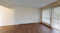 Located at 25246 106th Ave SE in Kent, Washington, this one-bedroom, one-bathroom home offers a well-organized single-floor layout designed for comfortable everyday living. Wood-look flooring flows consistently throughout the space, creating a cohesive and clean aesthetic anchored by neutral, light-toned walls and textured ceilings.

The living room is generously proportioned, featuring a ceiling fan with light fixture, baseboard heating, and large windows dressed with vertical blinds that allow ample natural light to filter in. A private balcony extends the living area outdoors. Two hallways connect the rooms efficiently, with four closets distributed throughout the home providing abundant storage.

The galley-style kitchen is thoughtfully appointed with white shaker-style cabinetry extending to the ceiling, a light stone-look countertop, a full suite of white appliances including an electric range, over-the-range microwave, and refrigerator, and wood-look flooring that ties into the rest of the home.

The bedroom offers a comfortable footprint with a window, baseboard heater, and direct closet access. The full bathroom features a white vanity with brushed nickel hardware, a tiled shower-tub combination, and matching wood-look flooring. The overall ambiance is bright, clean, and move-in ready.