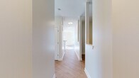 This well-appointed single-floor residence offers a clean, modern aesthetic defined by neutral tones, crisp white trim, and an abundance of natural light throughout. A welcoming hallway with light hardwood-style flooring connects the various areas of the home seamlessly.

The heart of the residence is a generous open-concept living and kitchen area. The kitchen is outfitted with white shaker-style cabinetry, granite countertops, stainless steel appliances including a refrigerator and microwave, and a large central island with pendant lighting above—ideal for both meal preparation and casual dining. The adjoining living space benefits from large windows that flood the room with natural light and offer views of the surrounding neighborhood.

The bedrooms feature plush carpeting and sizable windows that continue the home's bright, airy character. Each room provides a calm, versatile space adaptable to various needs.

The bathrooms are finished with light ceramic tile flooring. The primary bathroom includes a wide vanity with a granite countertop, white cabinetry, and a well-lit mirror, while a secondary bathroom offers a straightforward, functional layout.

Throughout the residence, consistent design choices—including white paneled doors, neutral wall colors, and quality flooring—create a cohesive and inviting living environment.