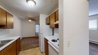 This apartment offers a practical and efficient living space. The kitchen, though compact, is fully equipped with essential appliances including a refrigerator, stove, and ample cabinet space. Wood-toned cabinetry contrasts nicely with white appliances and countertops, creating a clean, modern look. The living areas feature neutral-toned carpeting, providing comfort underfoot and helping to define separate spaces within the open floor plan. Large windows in the bedrooms allow for natural light, enhancing the sense of space. The bathroom, while modest in size, includes all necessary fixtures with a white color scheme that contributes to a bright, clean appearance. Baseboard heating units are visible in some rooms, indicating the property's climate control system. The overall design prioritizes functionality, with each area serving a clear purpose within the limited square footage. This apartment would be well-suited for individuals or couples seeking a no-frills, practical living space in an urban or suburban setting.